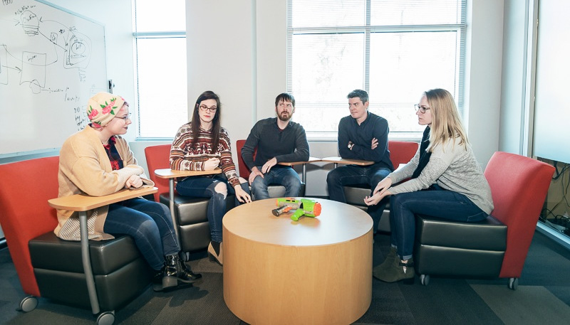 5 ABT employees around meeting table with nerf gun