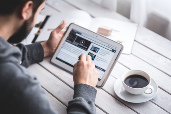 Man browsing web on tablet with coffee