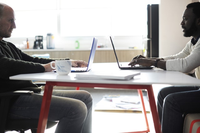 Two developers collaborating over laptops