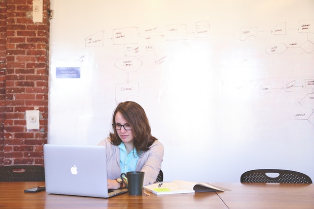 Woman at laptop in front of white board